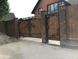 Изготовили и смонтировали кованных окатные ворота с калиткой, обшивка профлист под дерево, залили фундаментную ленту и произвели монтаж кирпичных столбов с колпаками, длина забора была 50м.п.